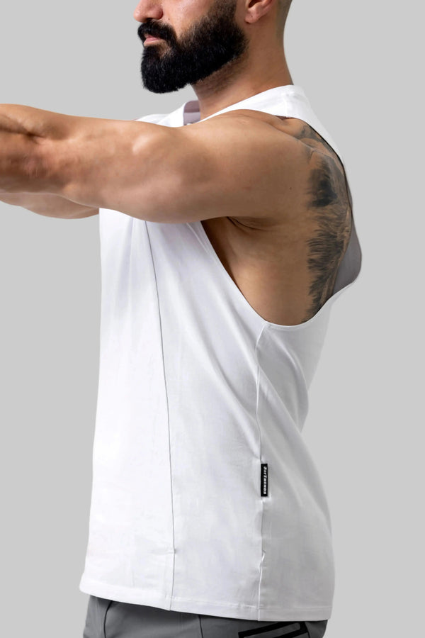 Man wearing a white sleeveless shirt with a visible brand logo on a plain background