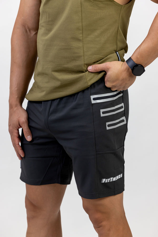 Person wearing black shorts with white branding and an olive green sleeveless top on a white background