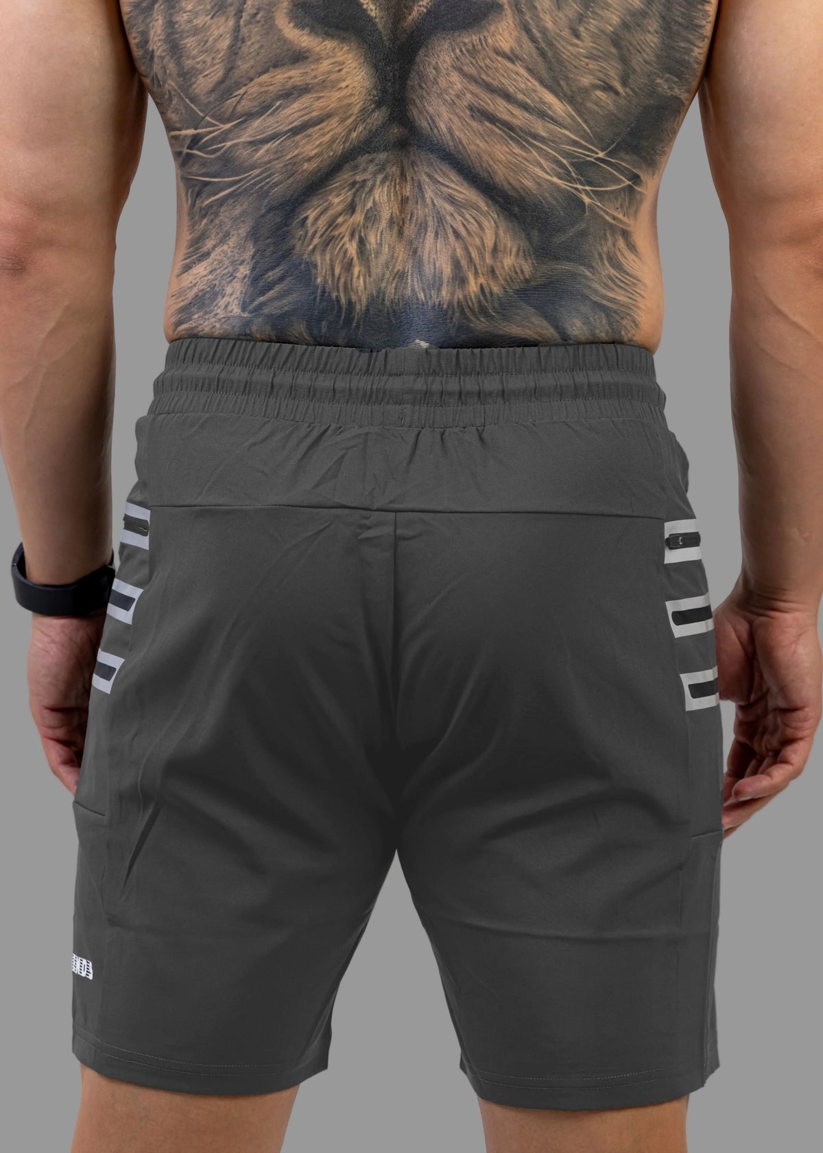 Person wearing black shorts with white stripes on a plain background