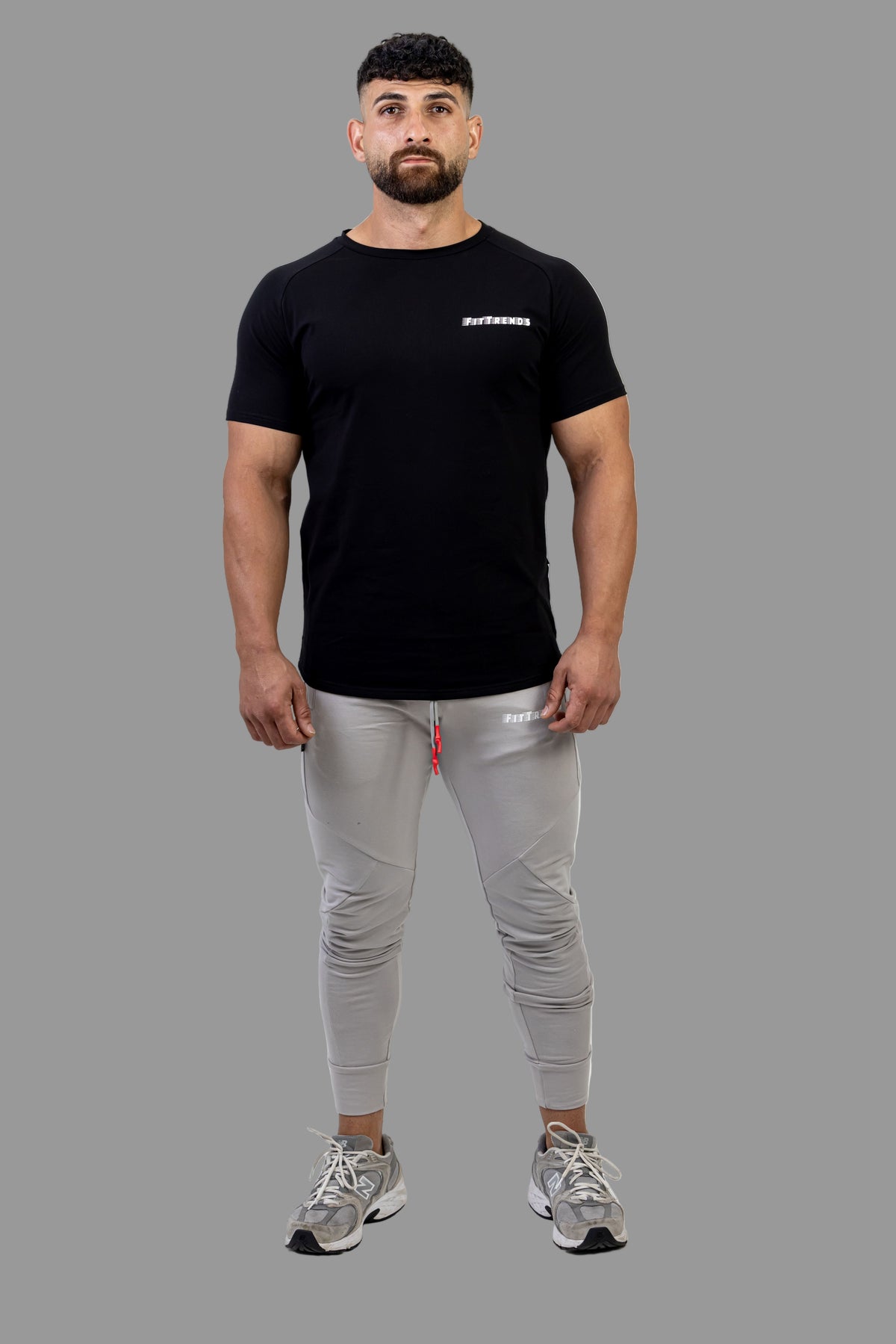 Man wearing a black t-shirt and gray jogger pants on a white background