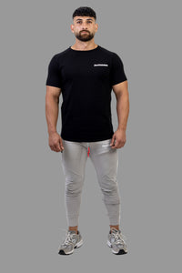 Man wearing a black t-shirt and gray jogger pants on a white background