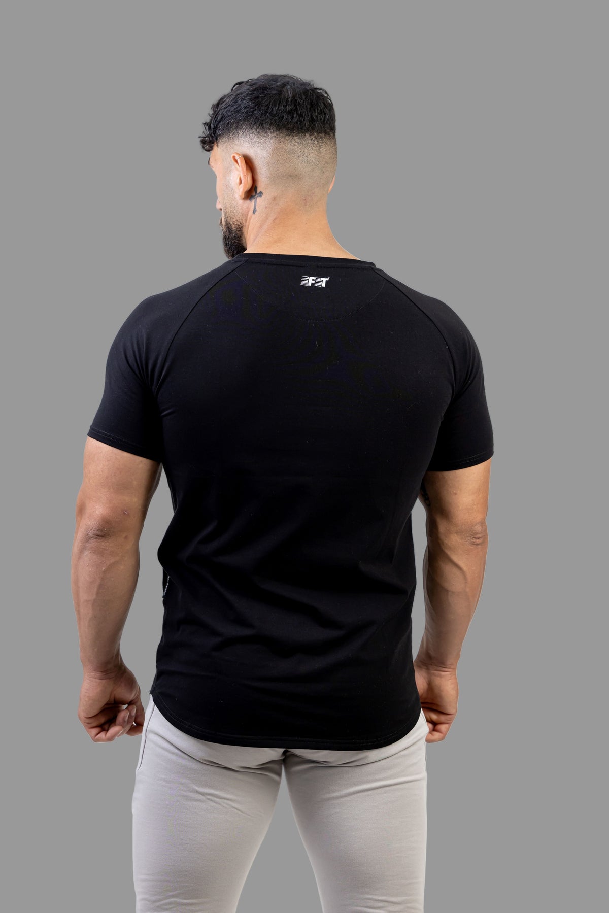 Man wearing a black t-shirt with a logo on the back against a white background