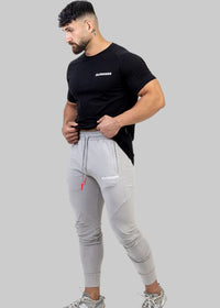 Man wearing a black t-shirt and gray jogger pants on a white background