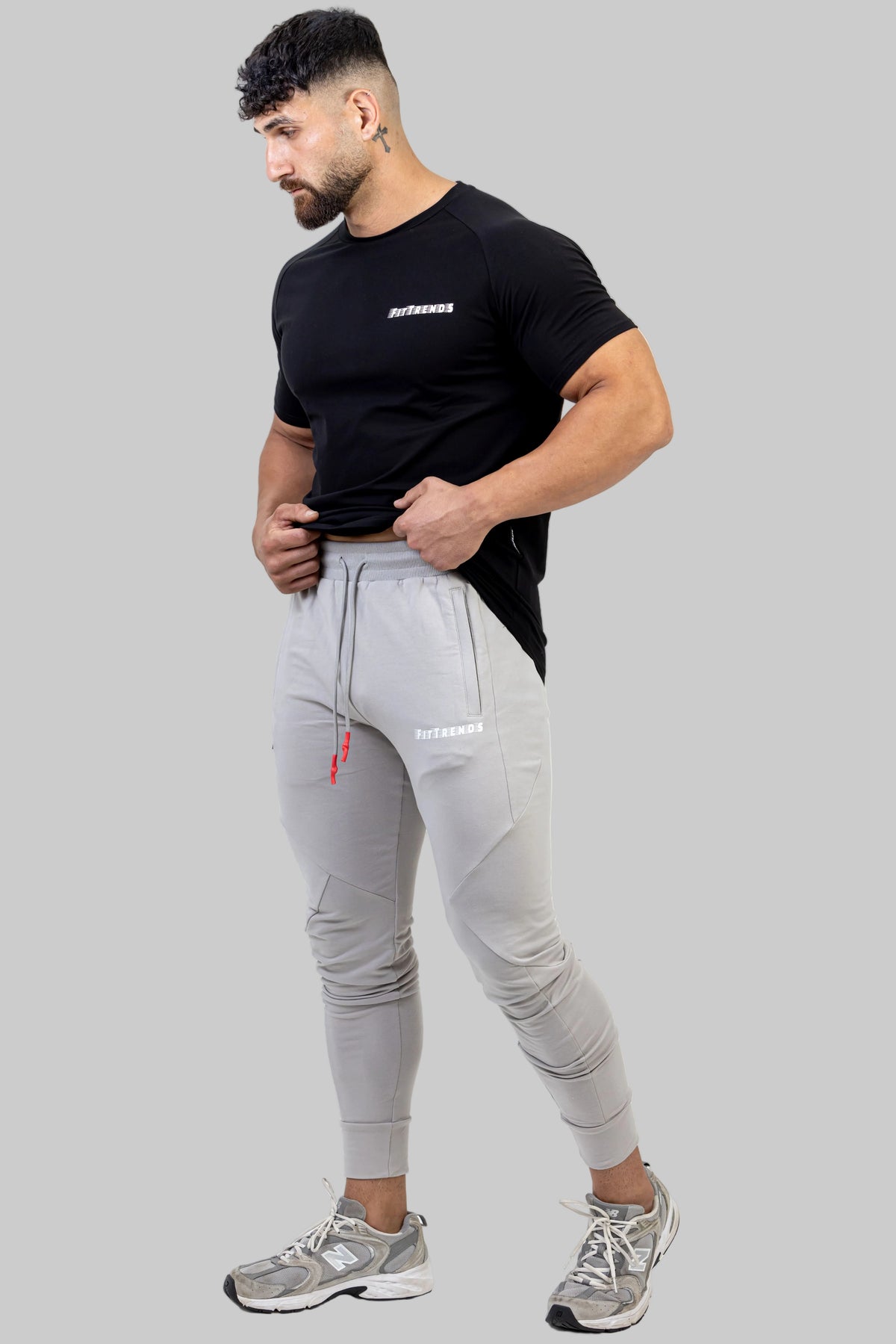 Man wearing a black t-shirt and gray jogger pants on a white background