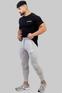 Man wearing a black t-shirt and gray jogger pants on a white background