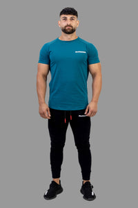 Man wearing a teal t-shirt and black pants on a white background