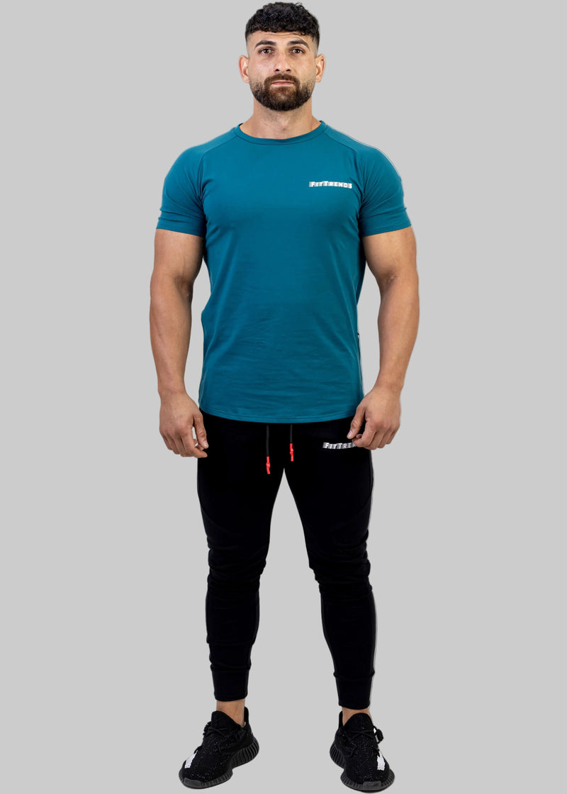 Man wearing a teal t-shirt and black pants on a white background