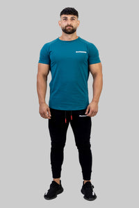 Man wearing a teal t-shirt and black pants on a white background