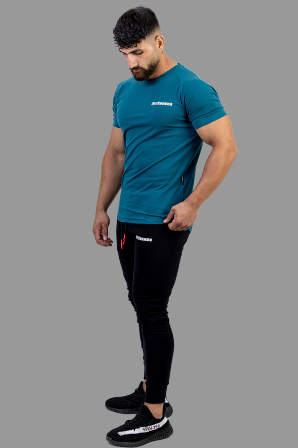 Man wearing a teal t-shirt and black pants on a white background