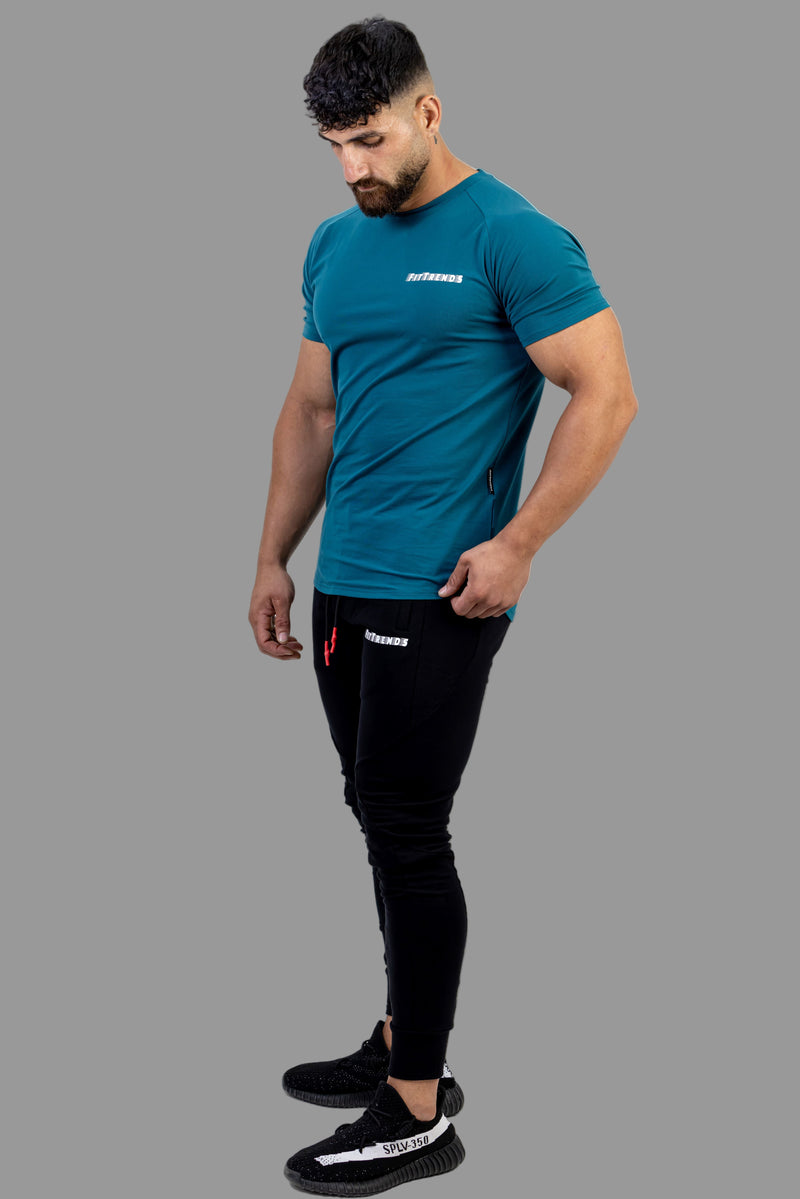 Man wearing a teal t-shirt and black pants on a white background