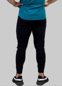 Man wearing a teal athletic shirt and black leggings on a white background