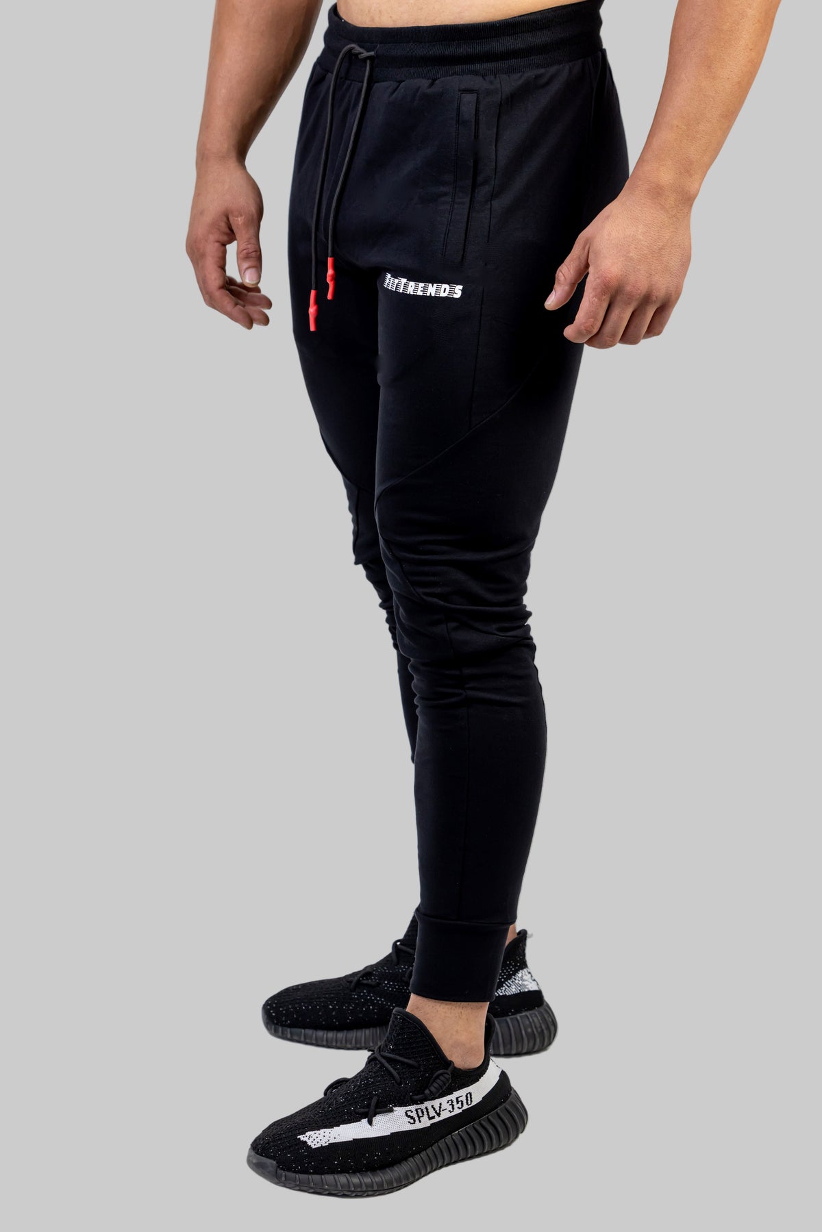 Person wearing black jogger pants with visible branding on a white background