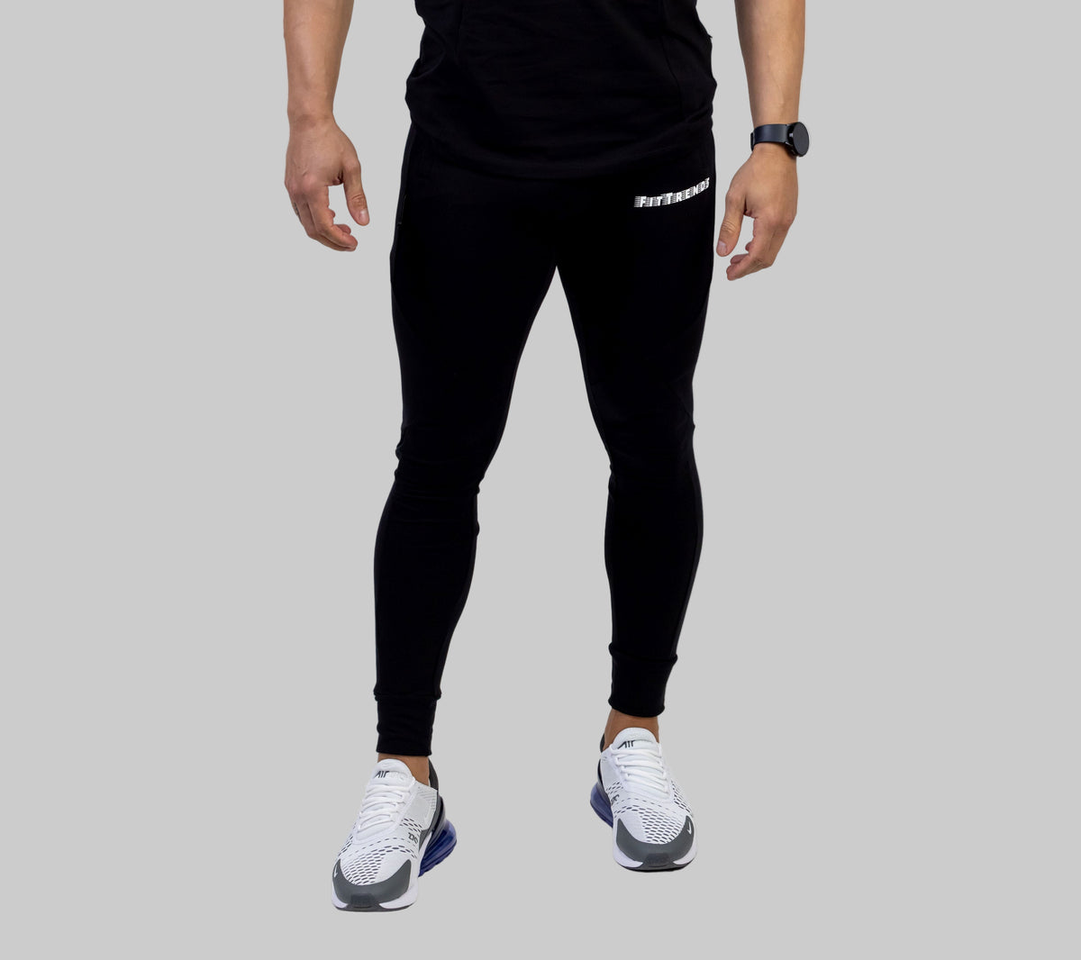Person wearing black athletic pants with a brand logo on a white background