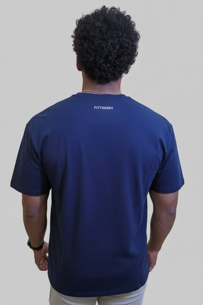 Person wearing a navy blue t-shirt with 'Fittrends' branding on the back, standing in front of a wall with large pink letters.