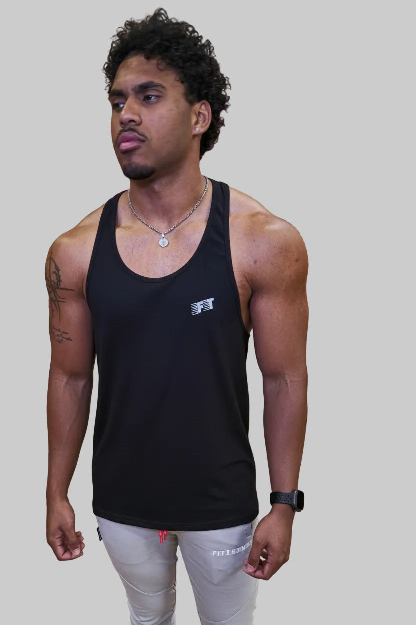 Man in black tank top standing in front of a wooden wall with pink text