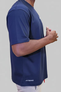 Person wearing a blue t-shirt with 'FITFRENDS' branding, standing against a wooden wall with pink text.