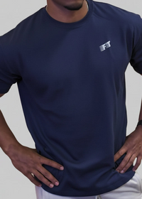 Person wearing a navy blue t-shirt with a logo on a gray background