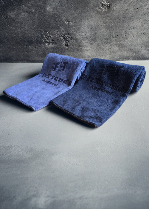 Two folded towels with a brand logo on a gray surface and background.
