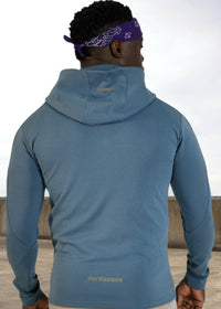 Person wearing a blue hoodie with a visible brand logo, standing outdoors.
