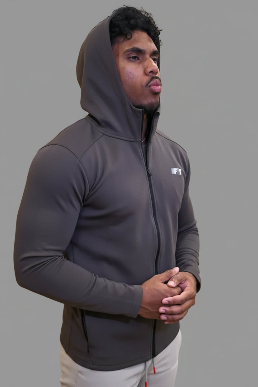Person wearing a dark gray hoodie with a brand logo, standing in a gym setting.