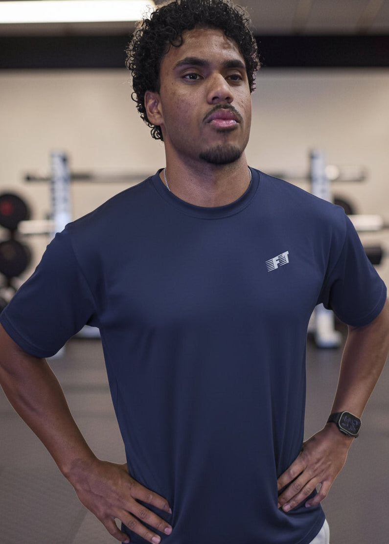 Man wearing a navy blue t-shirt with a logo in a gym setting