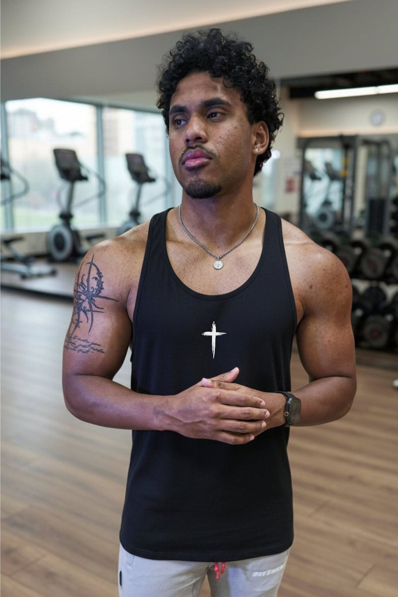 Man in a black tank top standing in a gym with a cross logo
