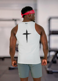 Person wearing a white tank top with a black cross design in a gym setting