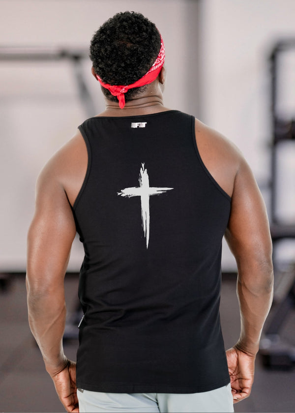 Person wearing a black tank top with a white cross design in a gym setting