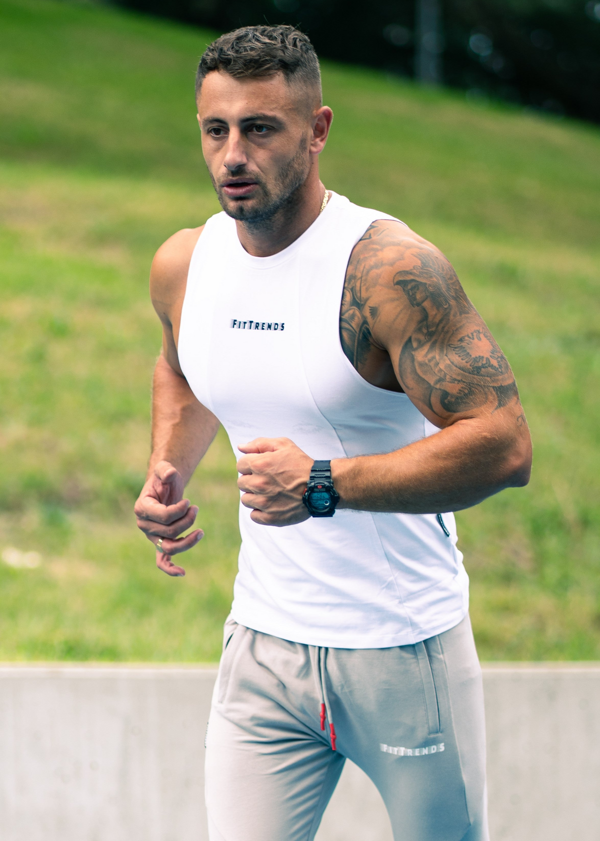 Man in athletic wear running on a track with grass and trees in the background