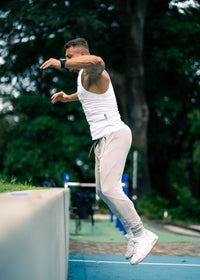 Person in athletic wear jumping on a tennis court with trees in the background