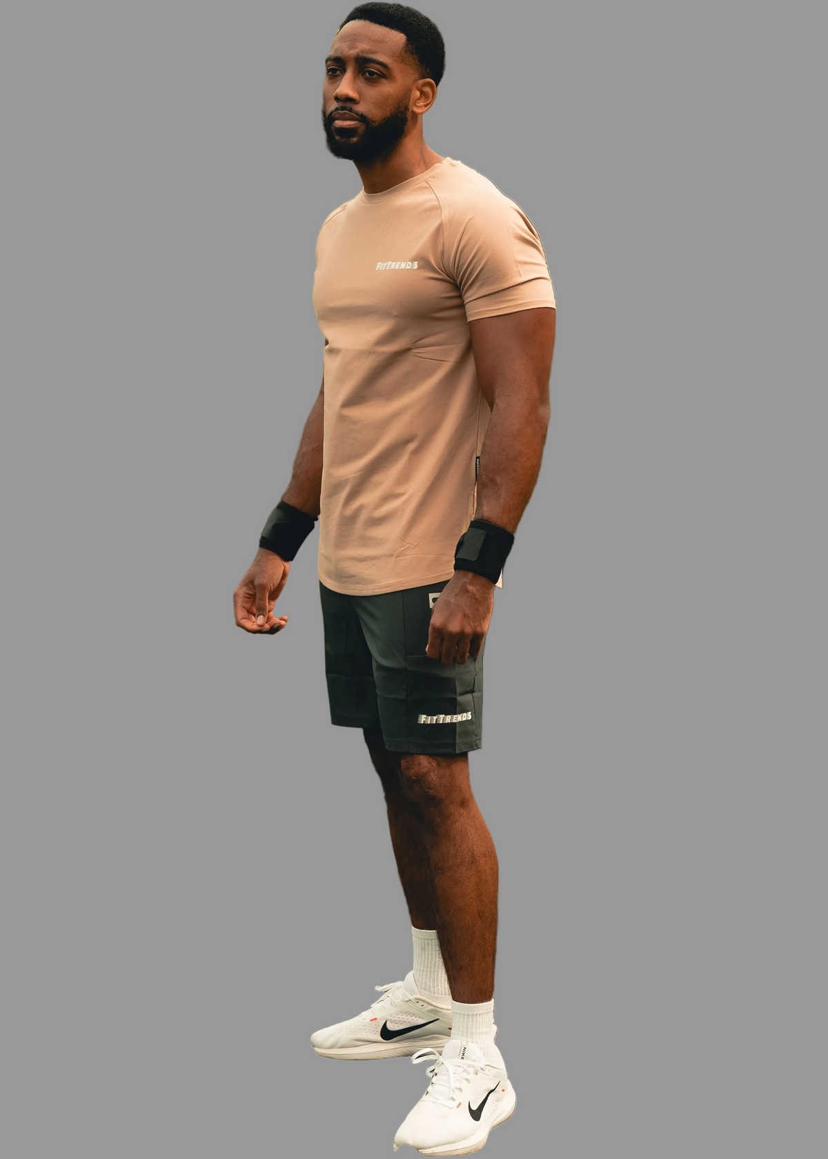 Man wearing a beige t-shirt and black shorts on a gray background