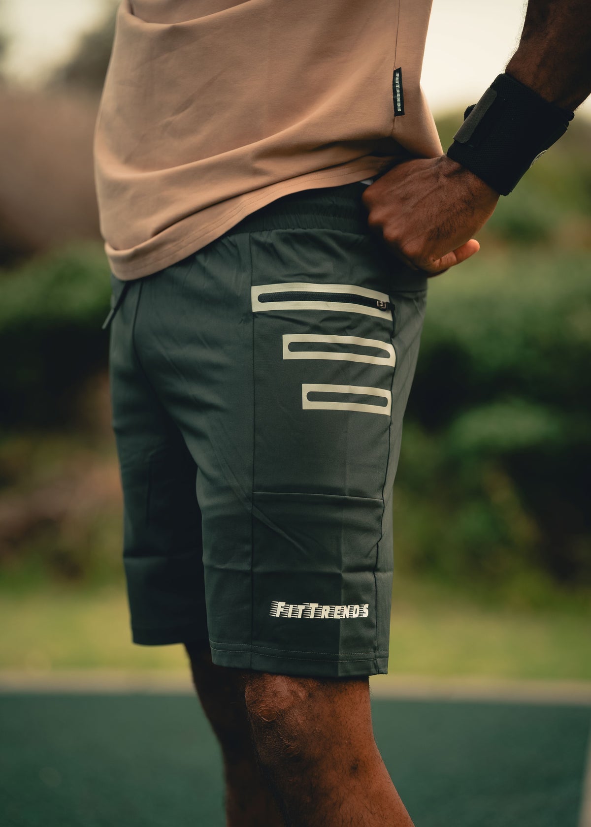 Person wearing green shorts with a brand logo, standing outdoors.