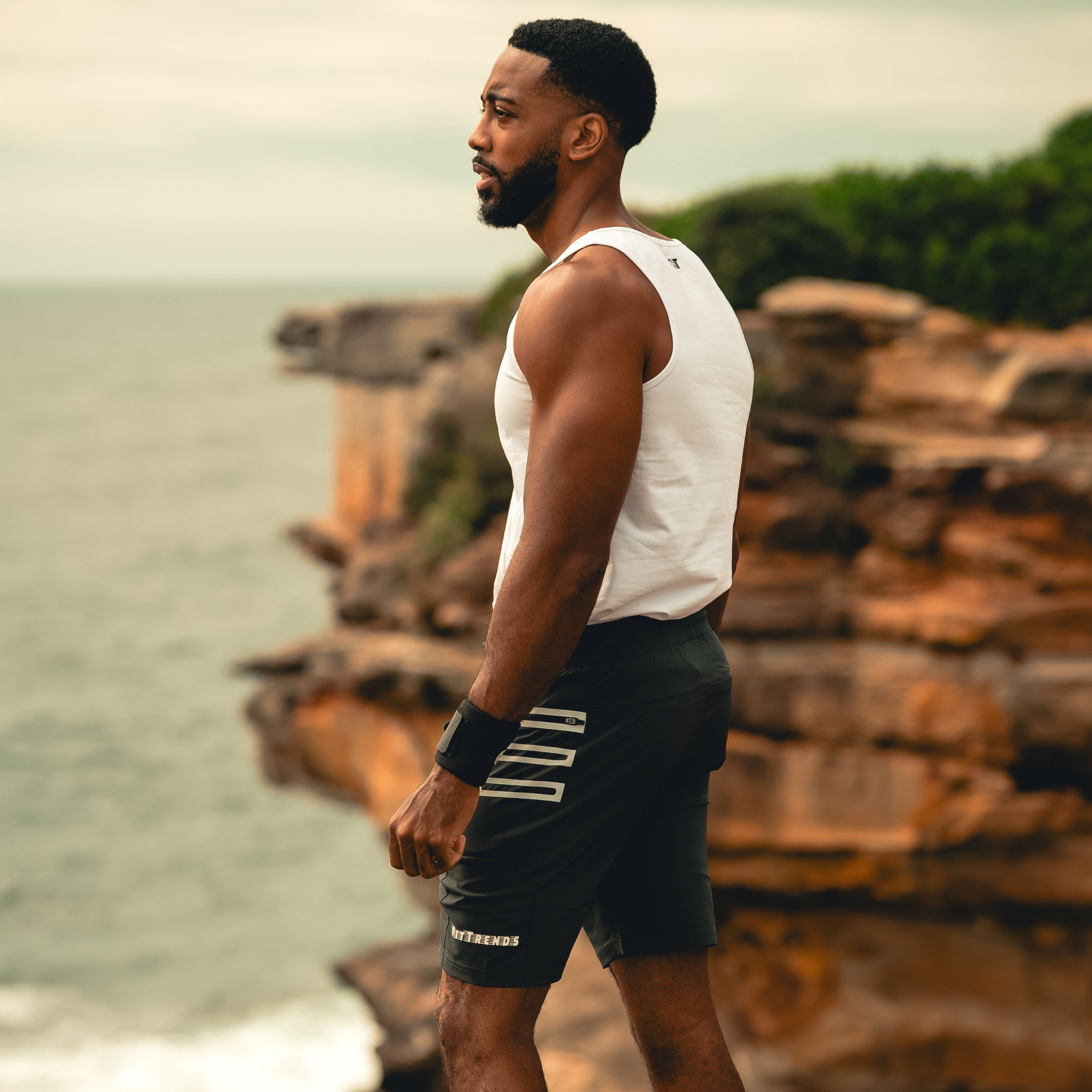 Man in athletic wear standing on a rocky coastal landscape