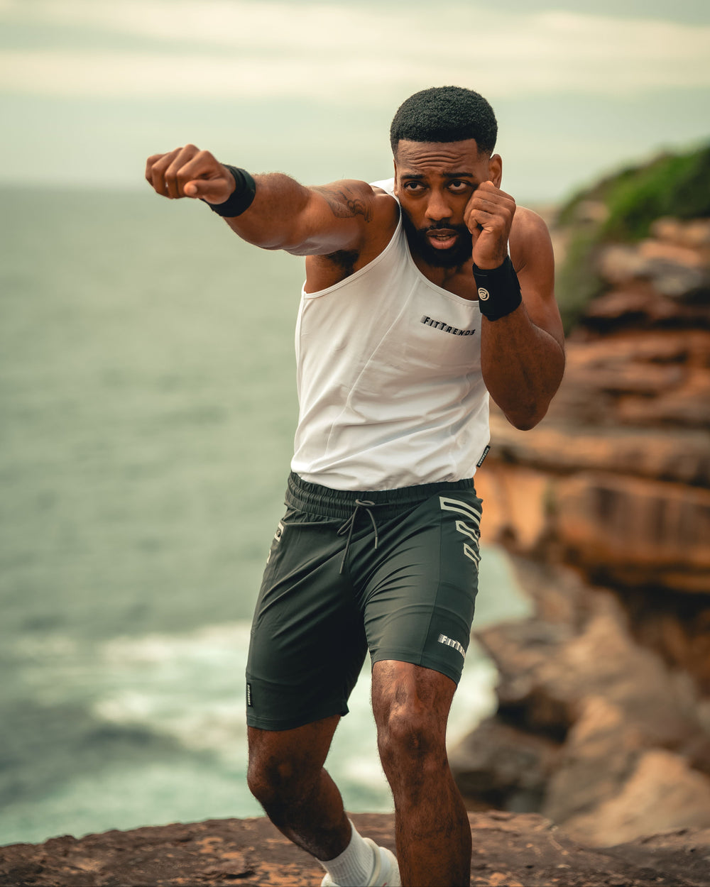 Man in athletic wear posing on a rocky cliff with ocean view