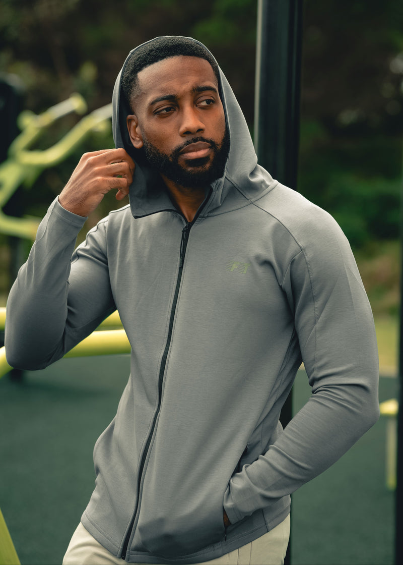 Man wearing a gray hoodie outdoors with a blurred background