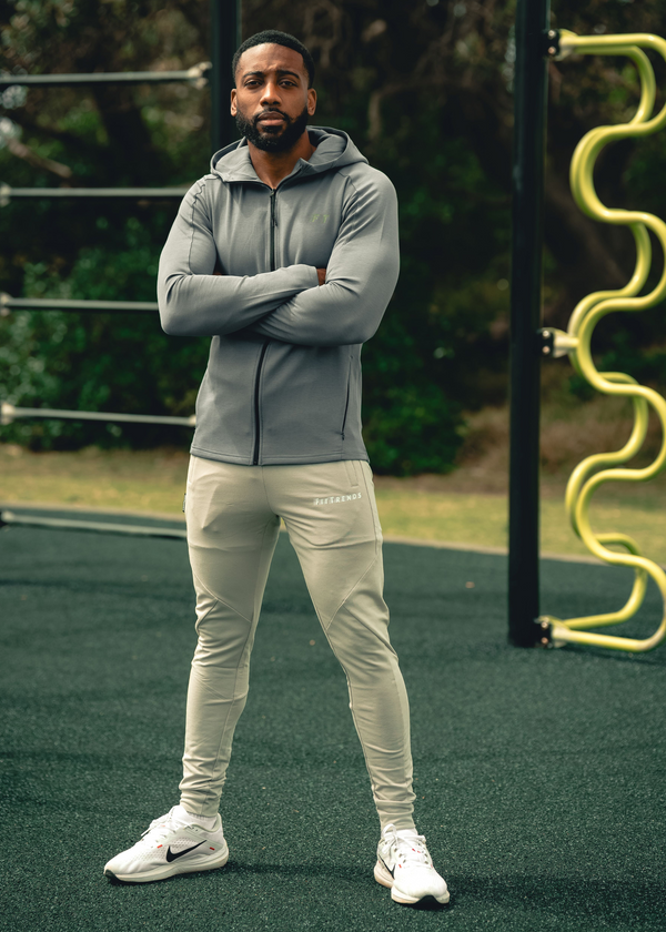Man wearing a gray hoodie and light-colored pants standing on a playground.