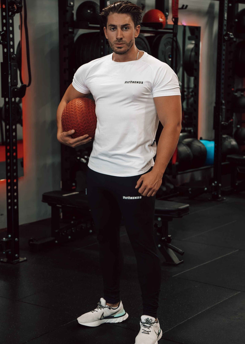 Man holding a basketball in a gym setting wearing FitTrends white T-Shirt