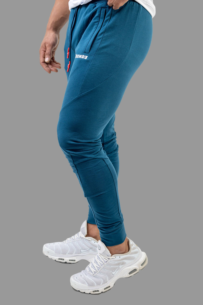 Person wearing blue jogger pants and white sneakers on a white background