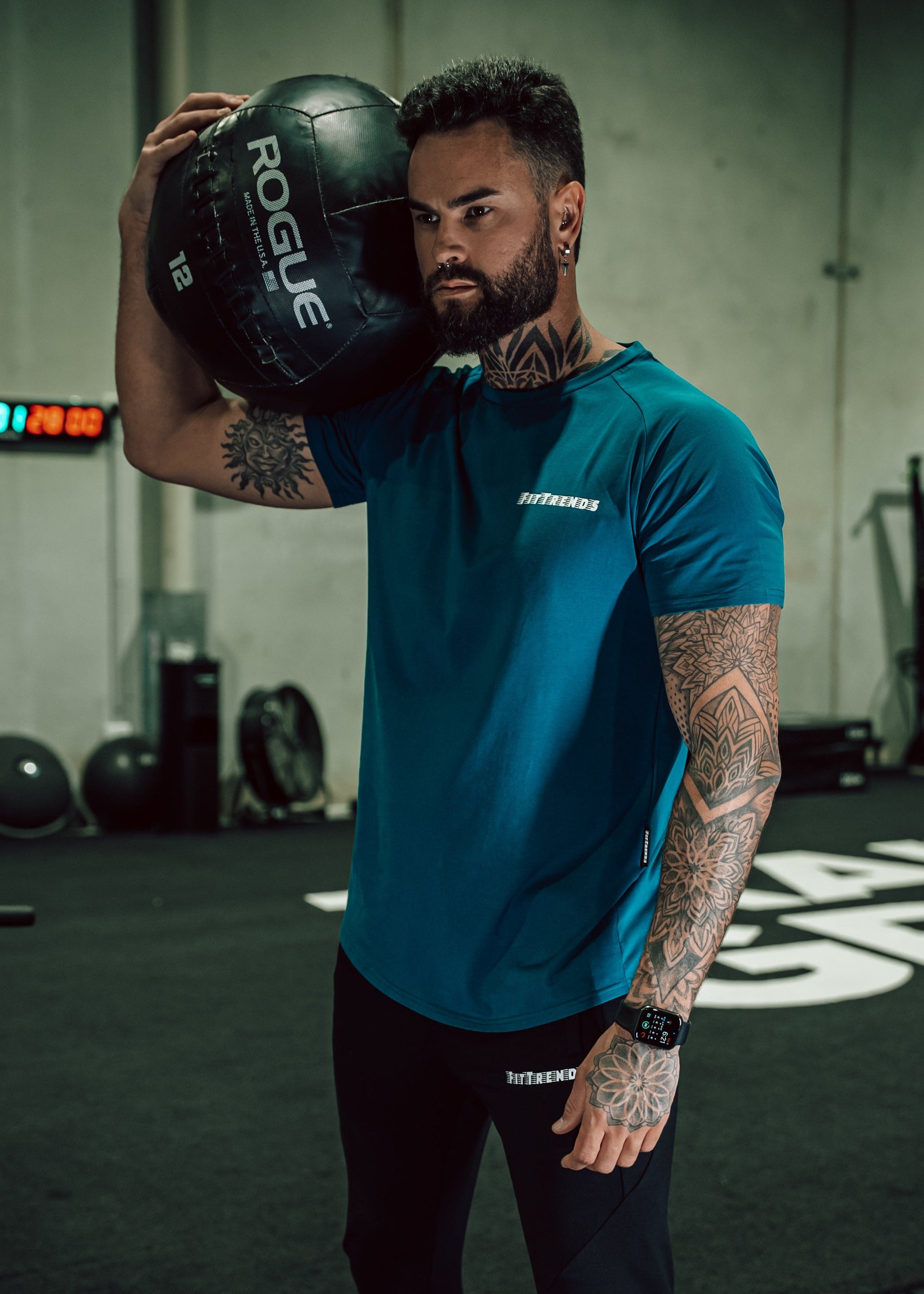 Man holding a Rogue fitness ball in a gym setting