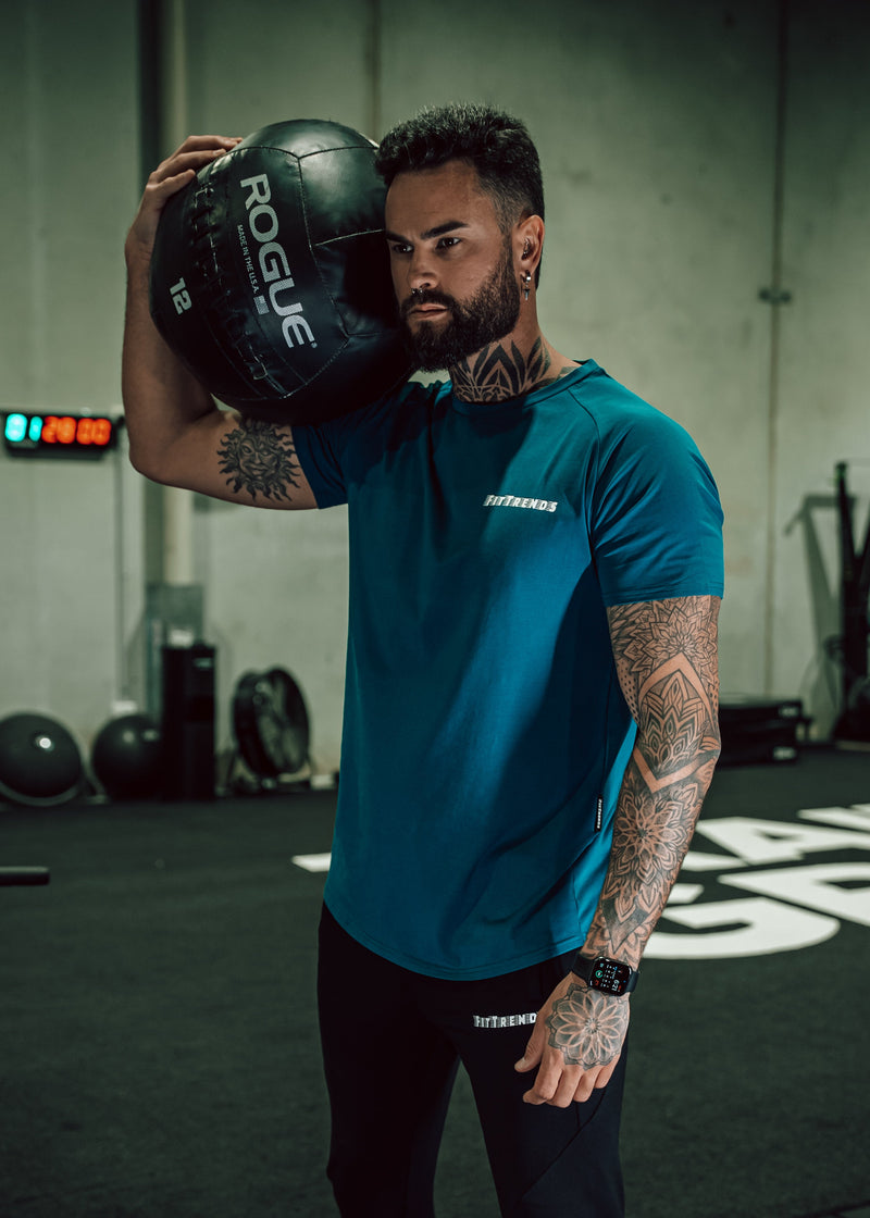 Man holding a Rogue fitness ball in a gym setting