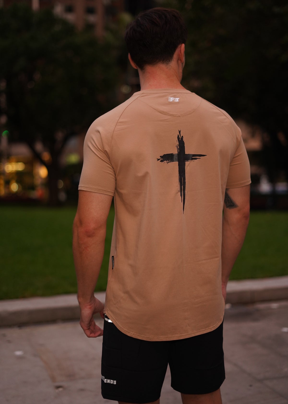 Person wearing a beige shirt with a black design outdoors