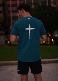 Person wearing a teal shirt with a white logo in an urban setting