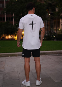 Person wearing a white t-shirt with a black logo outdoors at night.