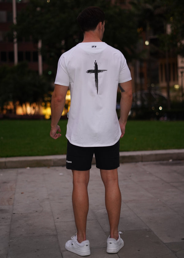 Person wearing a white t-shirt with a black logo outdoors at night.