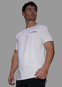 Man wearing a white shirt and black shorts standing outdoors with blurred background
