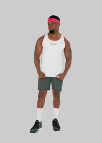 Man wearing a white tank top and gray shorts on a white background