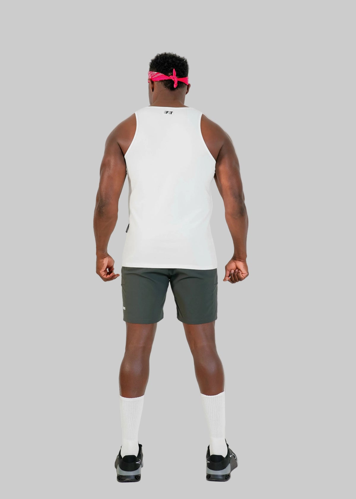 Person wearing a white tank top and green shorts on a white background