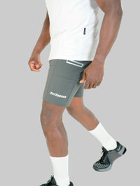 Person wearing gray athletic shorts with a brand logo on a white background