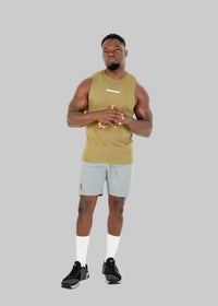 Man wearing a green tank top and gray shorts on a white background