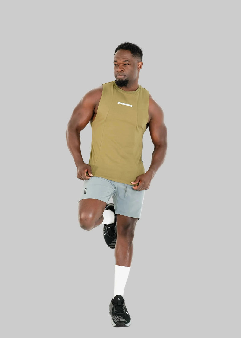 Man running on a white background wearing a sleeveless green top and light gray shorts.